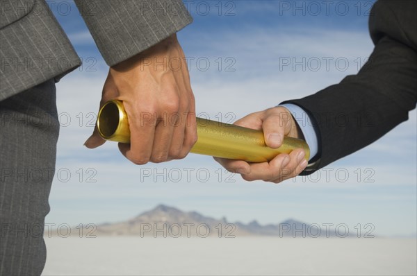 Businesspeople handing off baton in relay race, Salt Flats, Utah, United States. Date : 2007