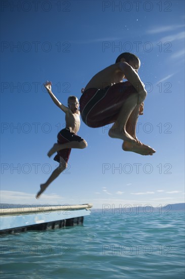 Brothers jumping off dock into lake, Utah, United States. Date : 2007