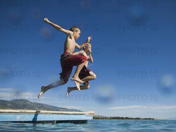 Brothers jumping off dock into lake, Utah, United States. Date : 2007