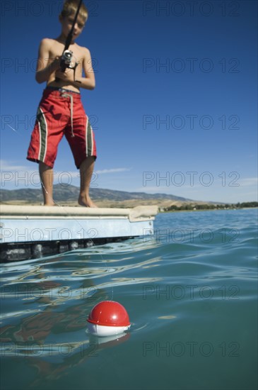 Boy fishing off dock in lake, Utah, United States. Date : 2007