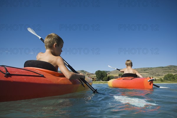 Brothers paddling in canoes on lake, Utah, United States. Date : 2007