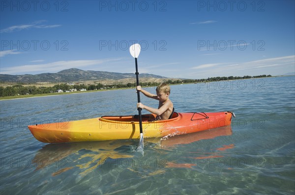 Boy paddling in canoe on lake, Utah, United States. Date : 2007