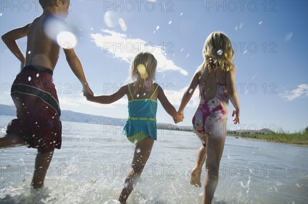 Brother and sisters running in water, Utah, United States. Date : 2007