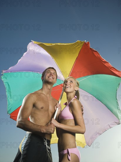 Couple standing under beach umbrella. Date : 2007