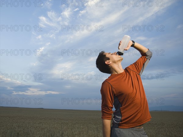 Man in athletic gear drinking water. Date : 2007