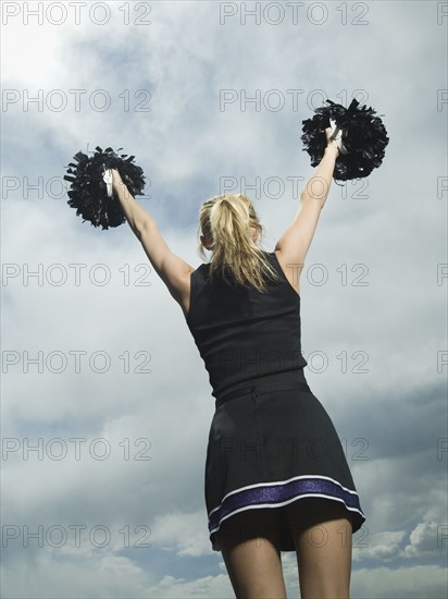Rear view of cheerleader with pom poms. Date : 2007