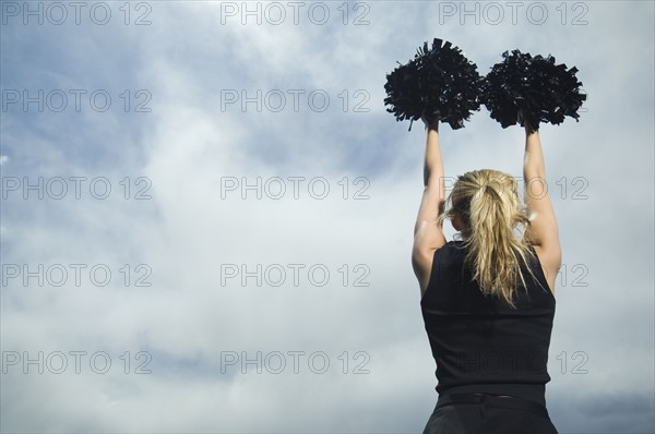 Rear view of cheerleader with pom poms. Date : 2007