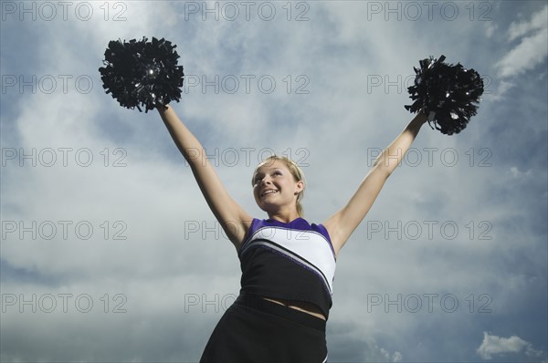 Cheerleader holding pom poms over head. Date : 2007