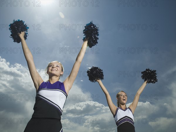 Two cheerleaders holding pom poms over head. Date : 2007