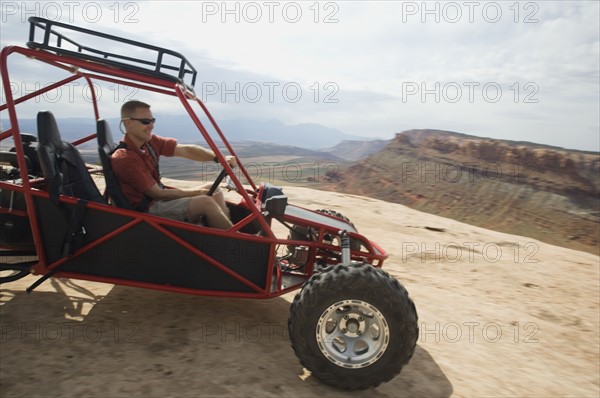 Man in off-road vehicle on rock formation. Date : 2007
