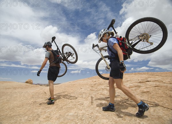 Couple carrying mountains bikes in desert. Date : 2007