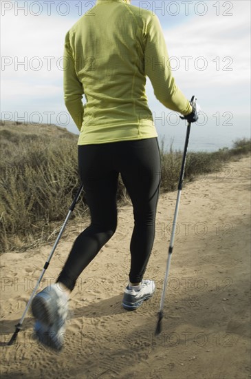 Hispanic woman pole walking along coast in California, United States. Date : 2007