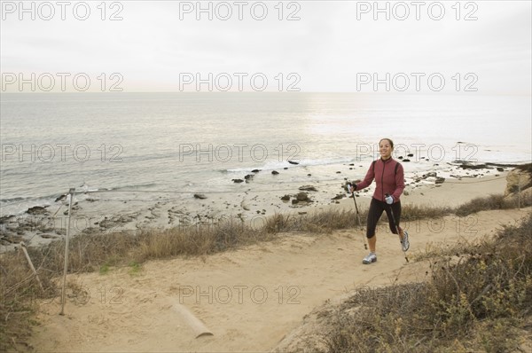 Hispanic woman pole walking along coast in California, United States. Date : 2007