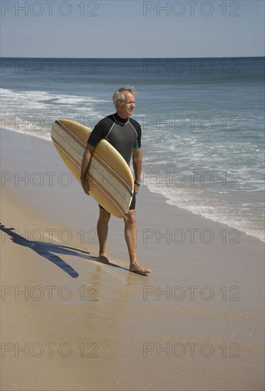 Man carrying surfboard at beach.