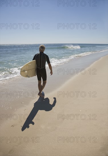 Man carrying surfboard at beach.