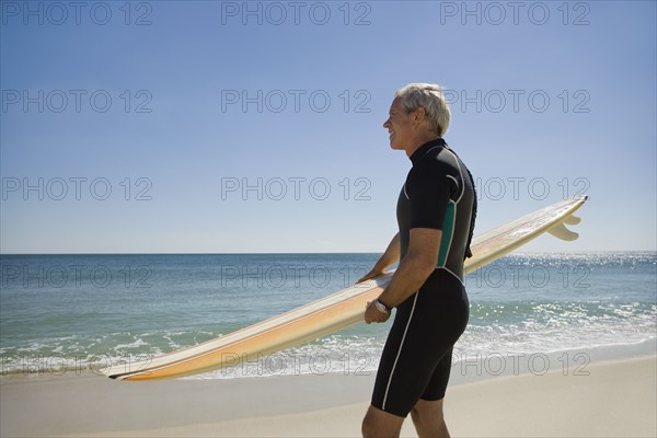 Man holding surfboard at beach.