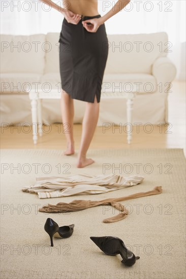 Woman undressing next to clothing on floor.