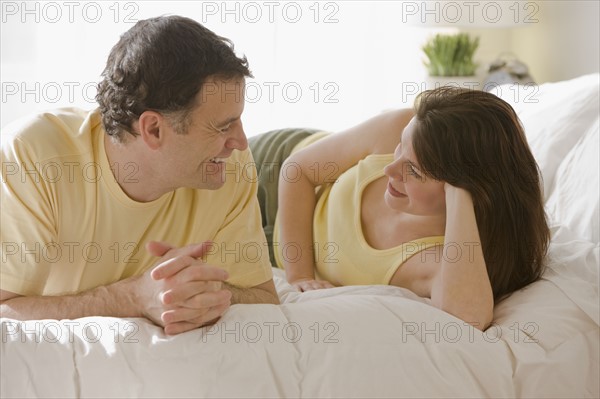 Couple talking on bed.