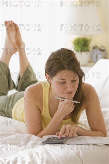 Woman doing finances on bed.