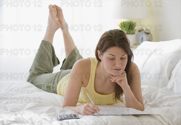 Woman doing finances on bed.