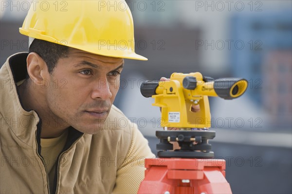 African male surveyor looking through measuring device.