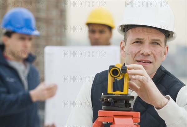 Male surveyor looking through measuring device.