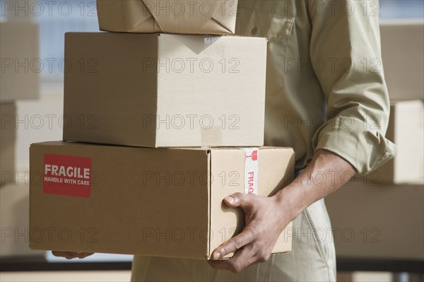 African delivery man carrying stack of packages.