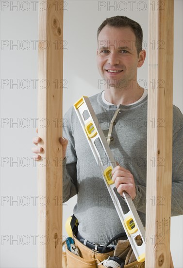 Male construction worker holding level tool.