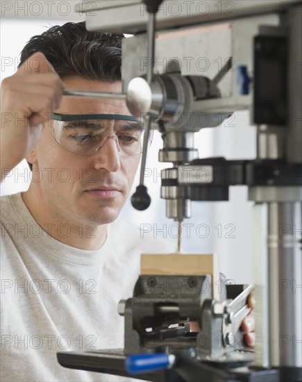 Man using drill press.