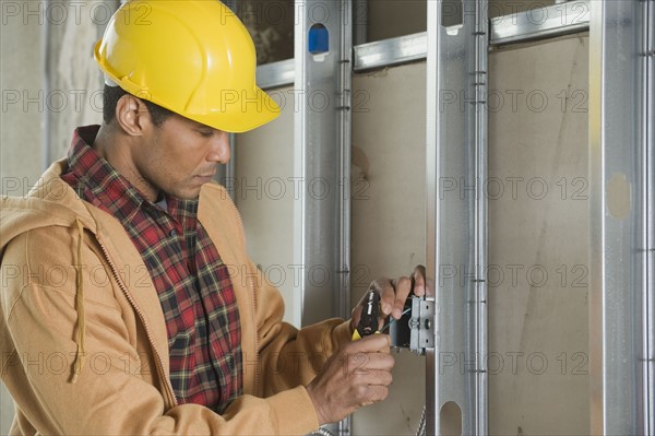 African male electrician installing wires.