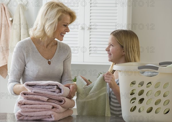 Grandmother and granddaughter folding laundry.