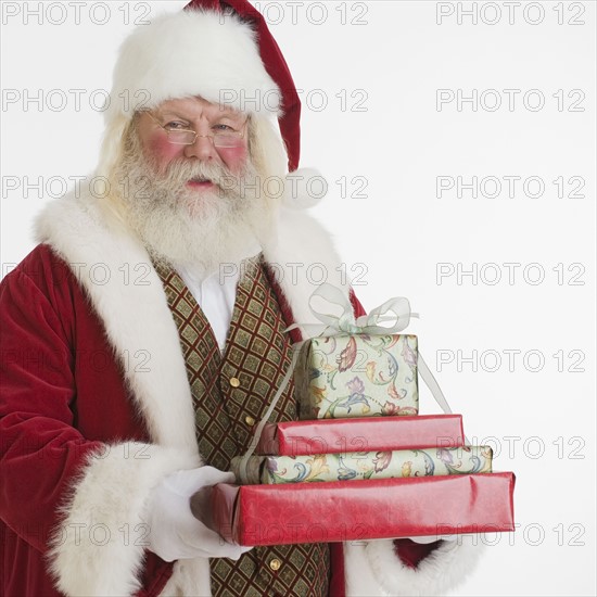 Santa Claus holding stack of gifts.