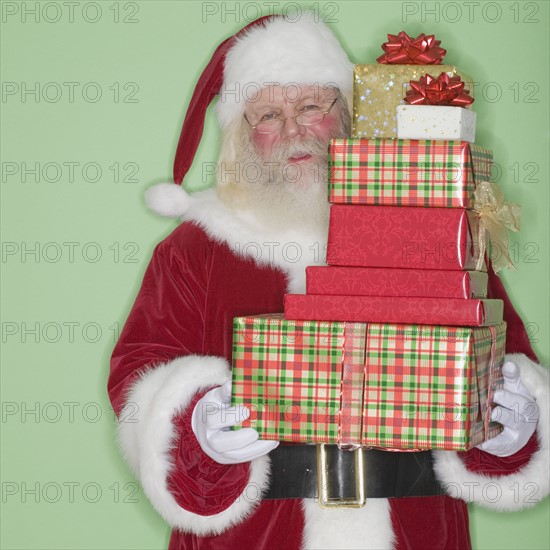 Santa Claus holding stack of gifts.