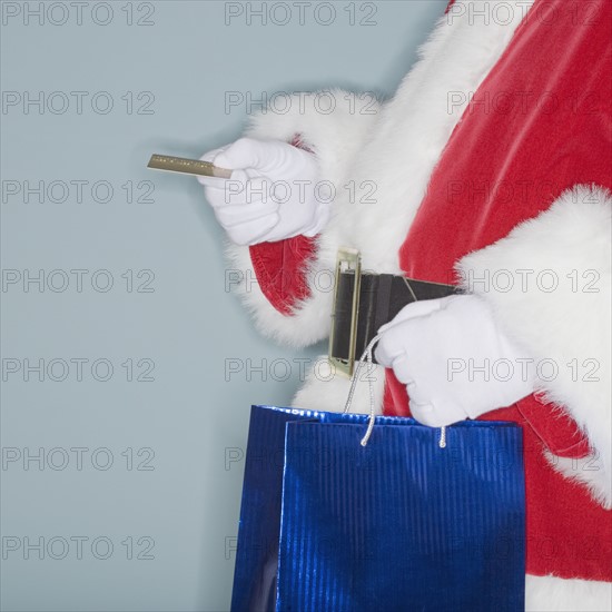 Santa Claus holding shopping bag and credit card.