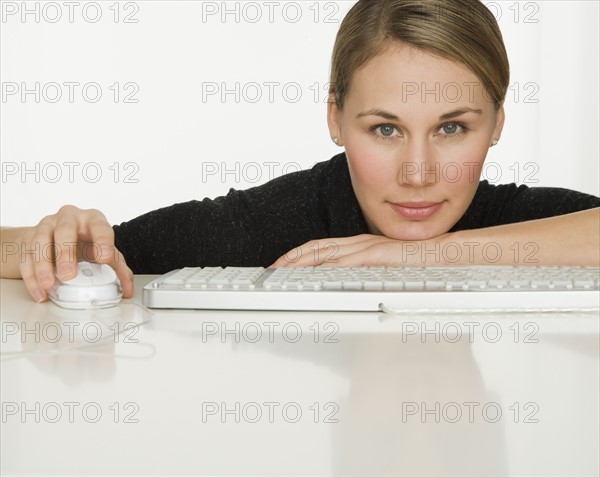 Woman leaning on table next to keyboard.