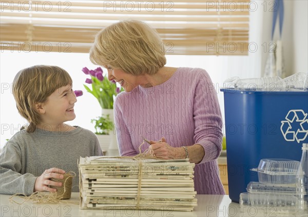 Grandmother and grandson recycling newspapers.