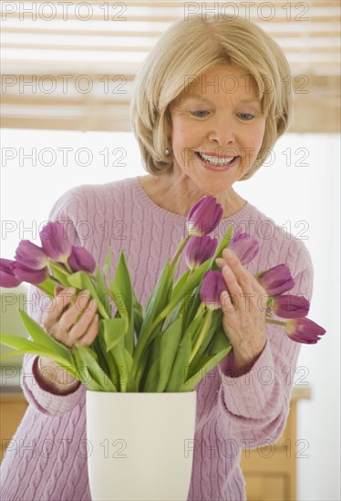 Senior woman arranging flowers.