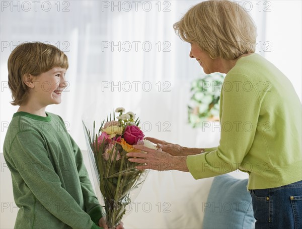 Grandson giving flowers to grandmother.