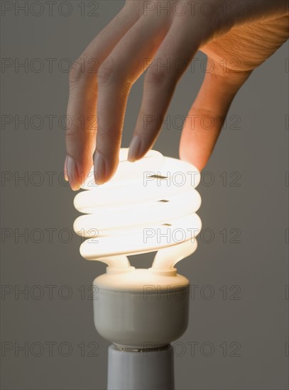 Woman screwing in energy-efficient light bulb.