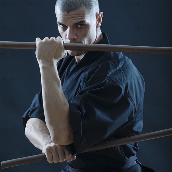 Hispanic male holding sticks in fighting stance.