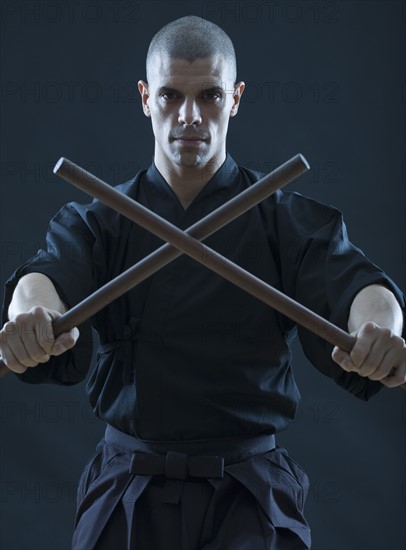 Hispanic male holding sticks in fighting stance.