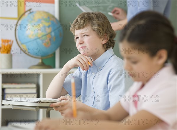 Boy thinking at school desk.