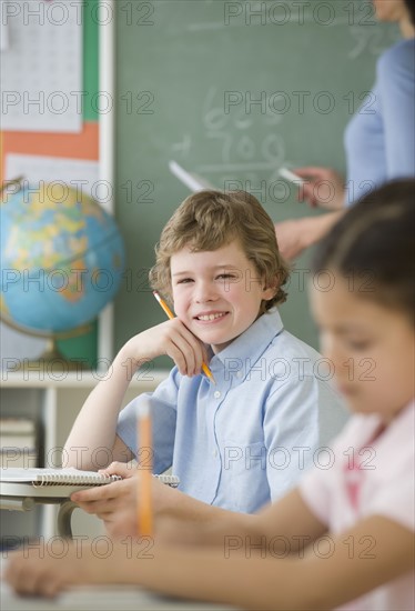 Boy holding pencil at school desk.