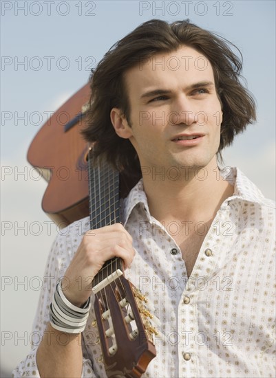 Man holding guitar on shoulder.