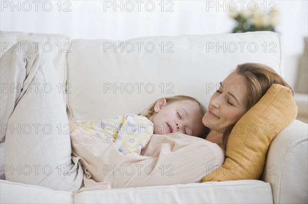 Mother and daughter sleeping on sofa.