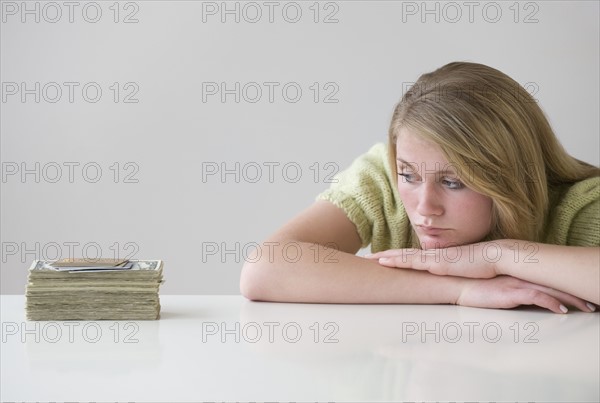 Teenaged girl looking at stack of money.