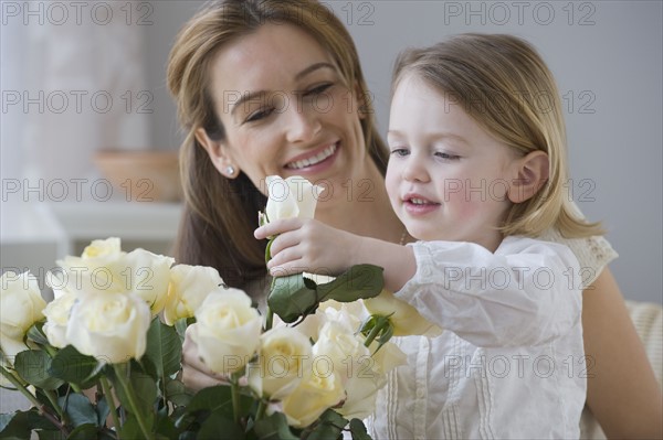 Mother watching daughter arrange flowers.