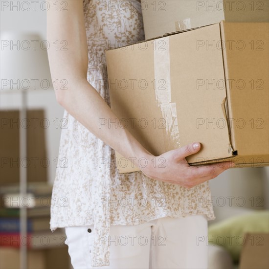 Woman carrying stack of moving boxes.