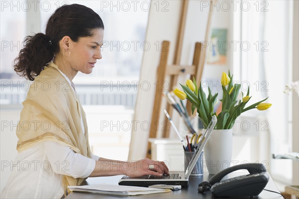 Hispanic woman typing on laptop.