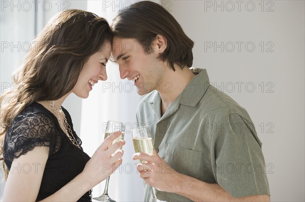 Couple holding champagne and touching foreheads.